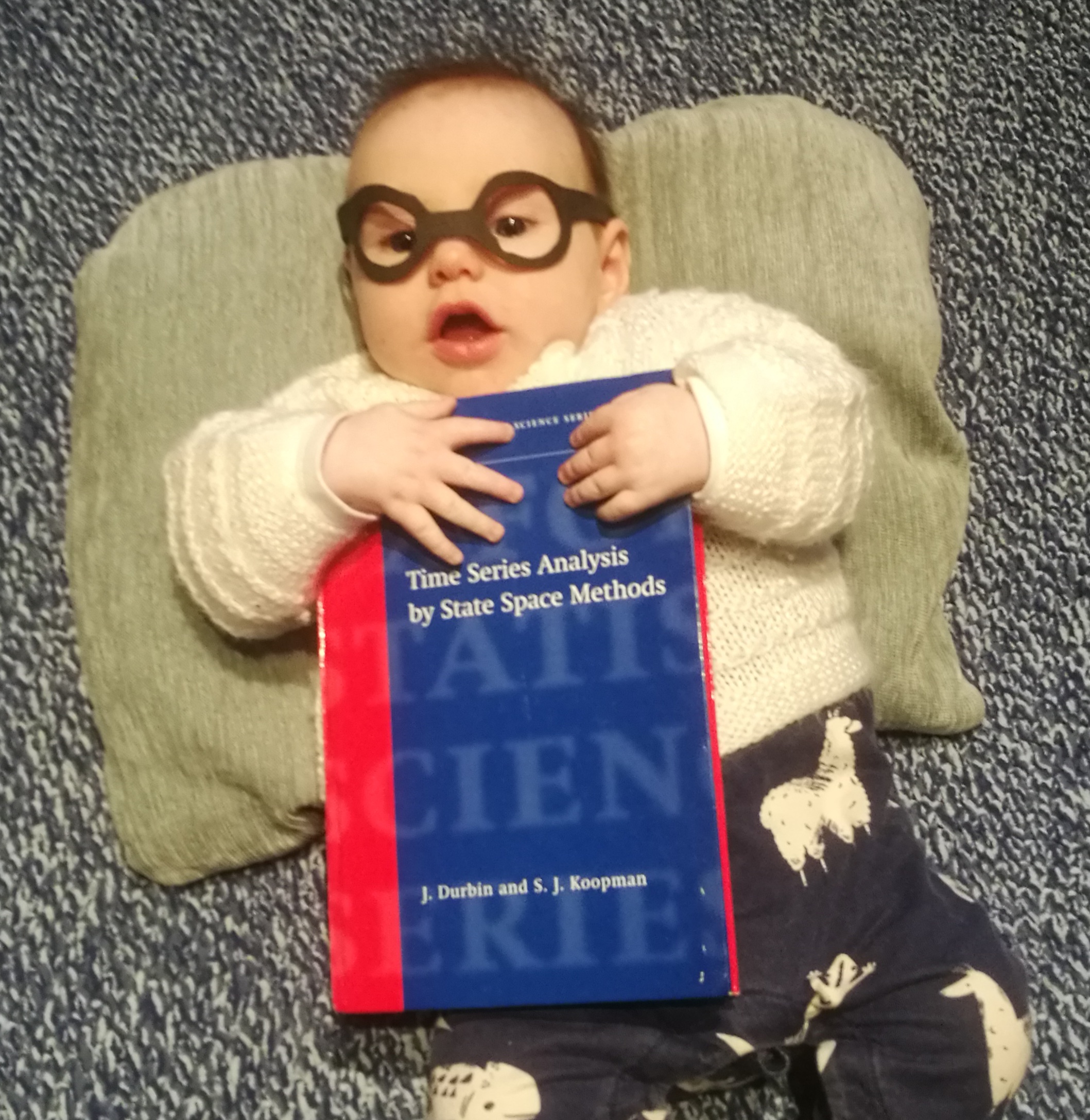 Baby holding mathematical textbook.